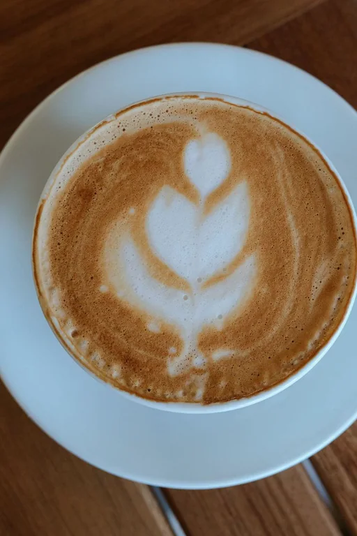 Xícara de cappuccino com arte no leite vista de cima sobre mesa de madeira