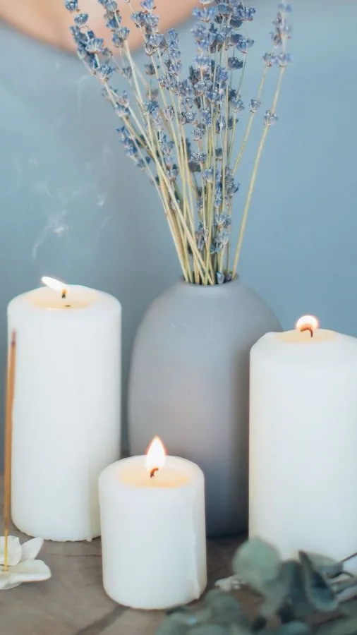 Velas acesas e vaso com lavanda em banquinho, com massagem desfocada ao fundo